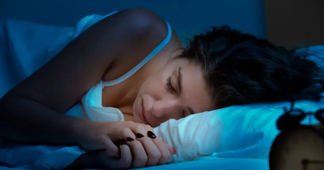 Kobieta śpi, ale budzik sugeruje, że to może być kolejna noc bez snu. Co to insomnia?