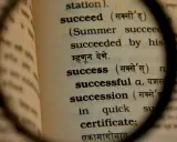 Słownik pod lupą ukazuje definicję słowa "success", czyli sukces. To droga do osiągnięcia celu.