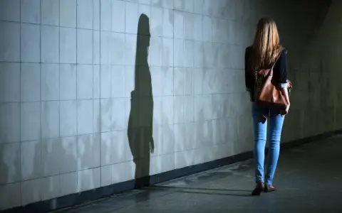 Dziewczyna z plecakiem idzie przez tunel, jej cień na ścianie symbolizuje dyfuzję odpowiedzialności.