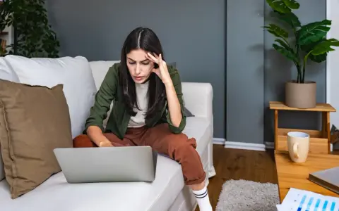 Introwertyczka skupiona na pracy przy laptopie na kanapie. Idealna praca dla introwertyka, gdzie można pracować w spokoju.